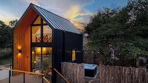 Une cabane moderne dotée d’un toit en pente, de grandes fenêtres et d’une terrasse en bois.