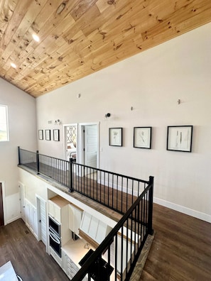 A multi-level interior with a wooden ceiling, a staircase, and a kitchen area.