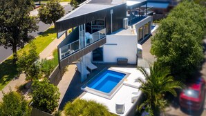 A modern house with a swimming pool, a covered outdoor area, and a view of the neighborhood. - Luxury Beachside Entertainer With Heated Pool (St Leonards)