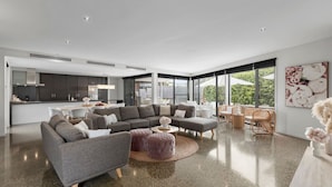 A modern living room with a sectional sofa, ottomans, and a coffee table. - Luxury Beachside Entertainer With Heated Pool (St Leonards)