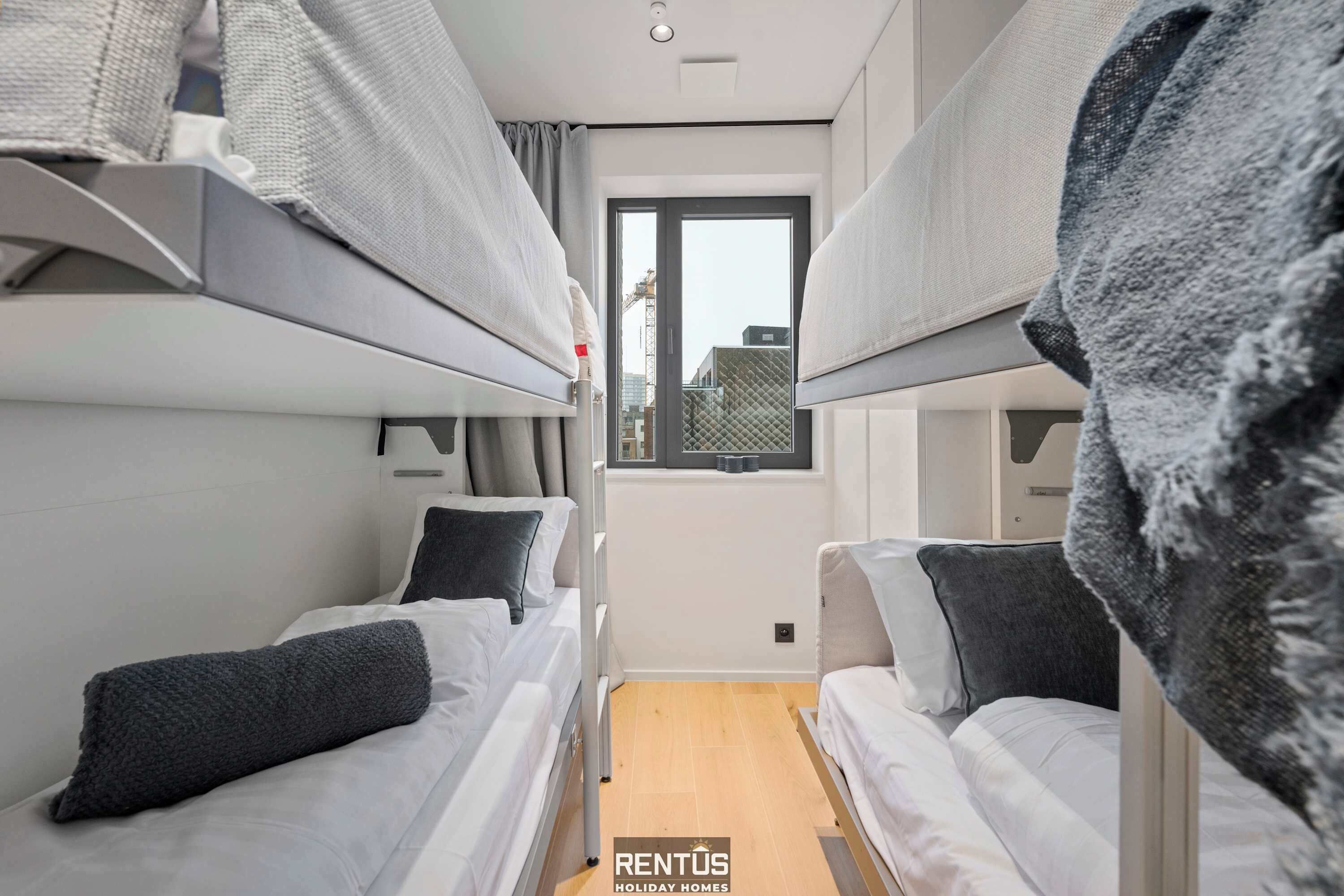 Une chambre d’hôtel compacte avec des lits superposés, une petite fenêtre et une vue sur l’extérieur.