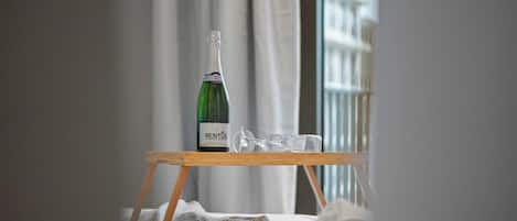 Eine Flasche RENTUS Wein steht auf einem Holztisch in einem Zimmer mit Blick auf Gebäude durch ein Fenster.
