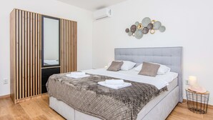 A modern bedroom with a bed, a wardrobe, a mirror, and a wall art piece. - Beautiful apartment in Vir (Vir)