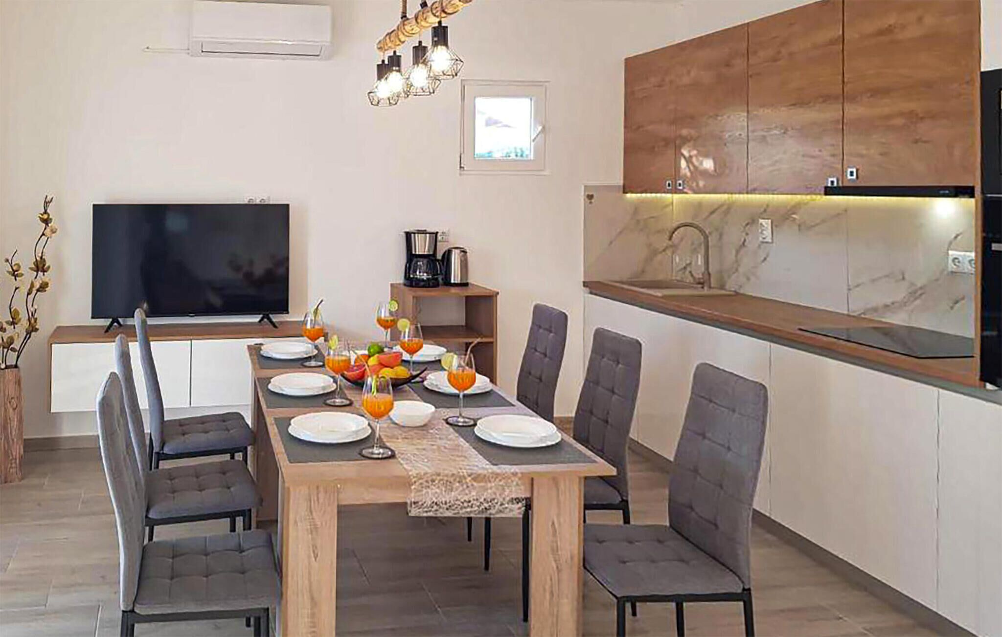 Una cocina moderna con comedor, televisor de pantalla plana y zona de desayuno.