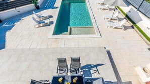 An outdoor swimming pool with lounge chairs and a table with drinks and fruits. - Beautiful apartment in Vir (Vir)