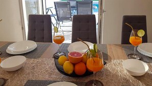 A dining table set with plates, glasses, and a fruit bowl with oranges and a grapefruit. - Beautiful apartment in Vir (Vir)
