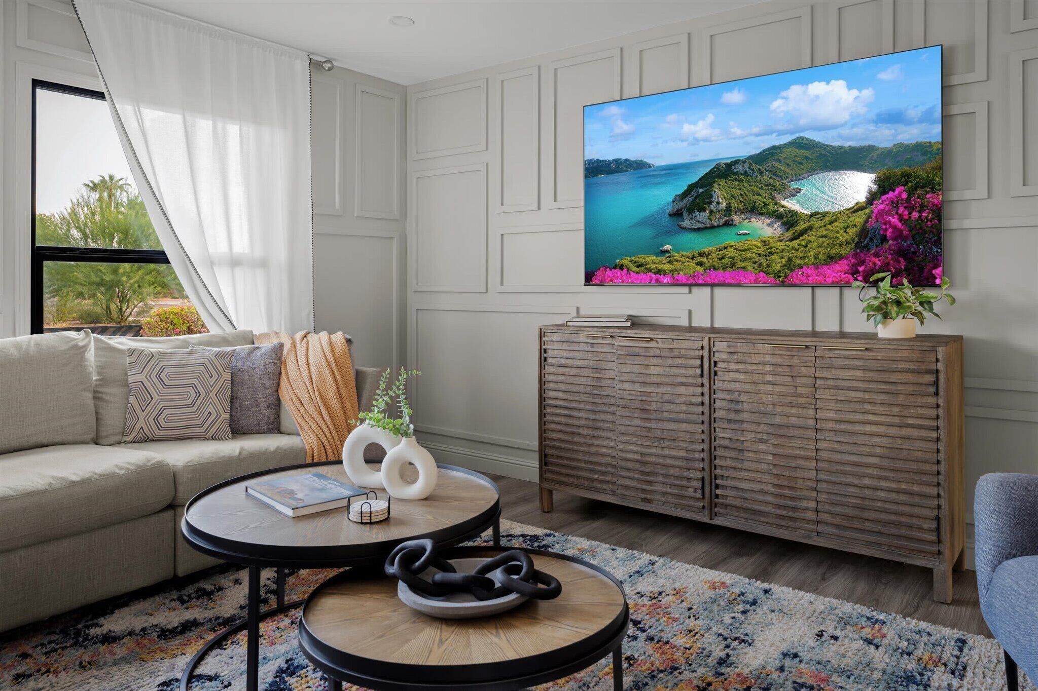 Una sala moderna con un televisor de pantalla plana grande, un sofá, una mesa de centro y un mueble de madera.