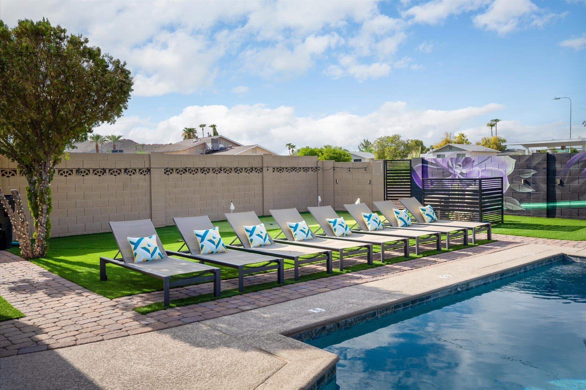 Un espace piscine avec des chaises longues et un mur décoratif.