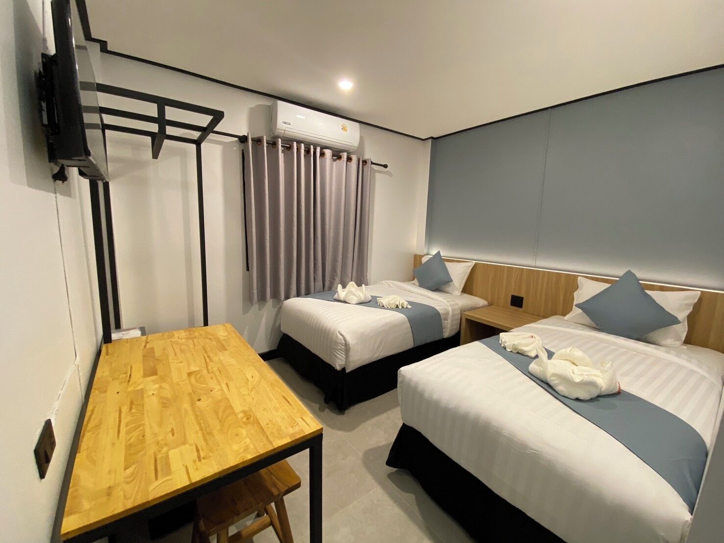 Una habitación de hotel con dos camas, una mesa de madera y un equipo de aire acondicionado.