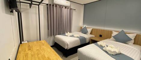 Una habitación de hotel con dos camas, una mesa de madera y un equipo de aire acondicionado.