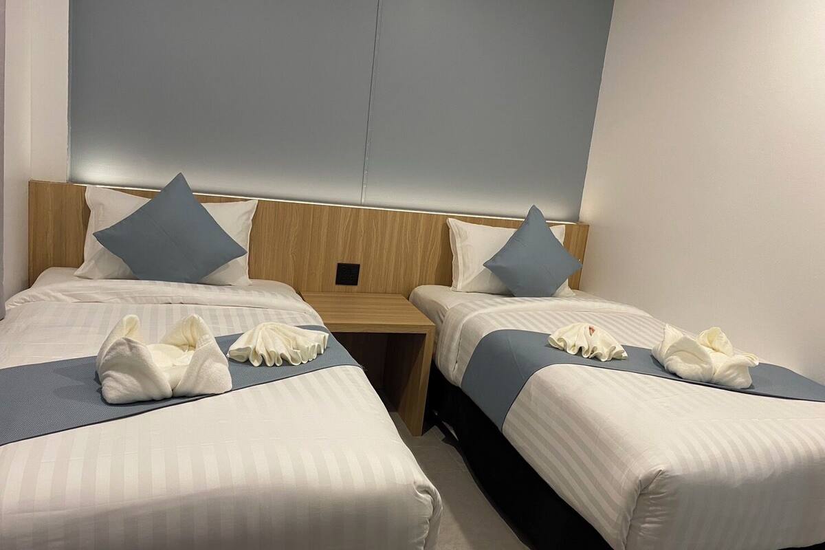 Une chambre d’hôtel avec deux lits, chacun étant équipé d’un oreiller et d’une serviette.