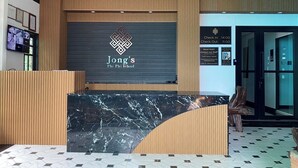 A reception desk with a logo, a check-in/out board, and a staff contact number.