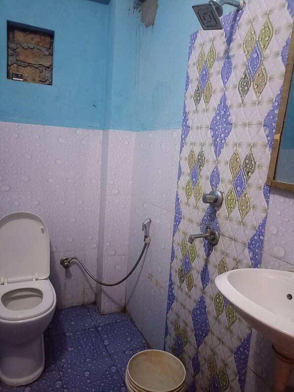 A small bathroom with a toilet, a sink, and a shower. - Laliguras Hotel and Lodge  (Manthali)