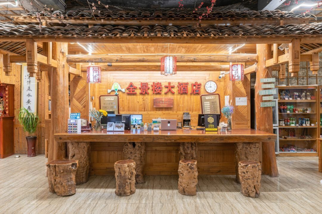 A traditional wooden interior with a reception desk, wooden stools, and a tiled ceiling.