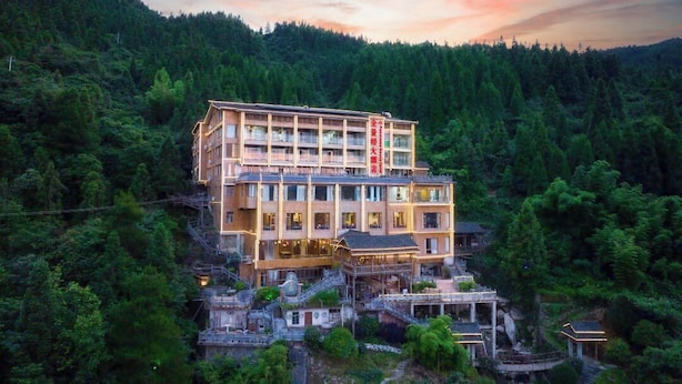 Un hotel a più piani dallo stile architettonico tradizionale, immerso in una fitta foresta.