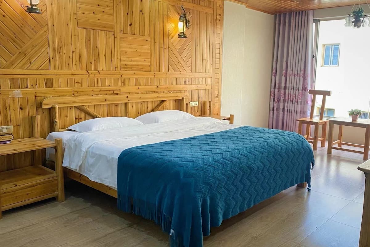 A wooden room with a bed, a nightstand, a table, and a chair.