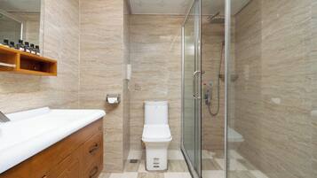 A modern bathroom with a glass shower enclosure, a white toilet, and a wooden vanity with a white countertop.