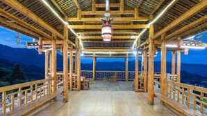 Un terrazzo in legno con vista sulle montagne, ringhiere di legno e un lampadario.