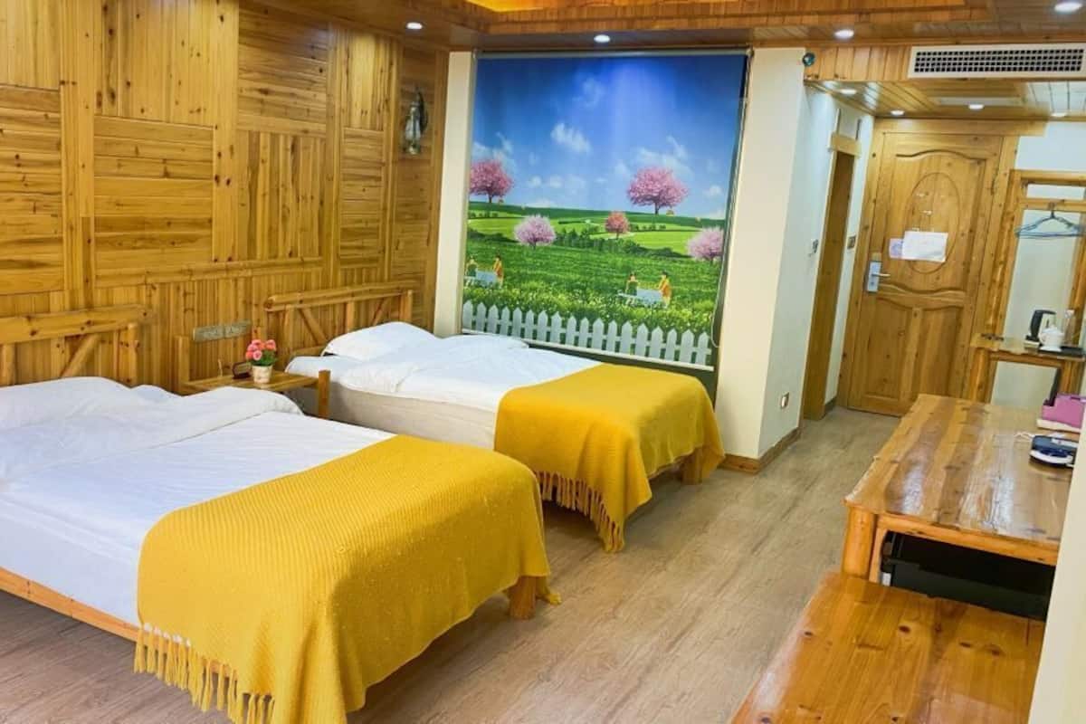 A wooden-themed room with two beds, a wooden desk, and a mural of a landscape.