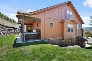 A two-story house with a stone foundation, a covered porch, and a stone retaining wall.