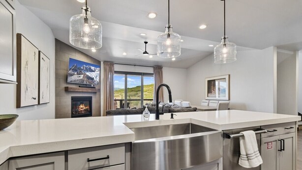 Una cocina moderna con una isla grande, electrodomésticos de acero inoxidable, luces colgantes y una chimenea.