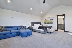 Une chambre à coucher avec un lit, un canapé bleu, une table de chevet et un tableau accroché au mur.