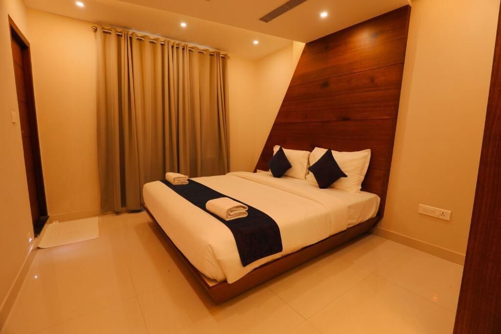 Une chambre d’hôtel moderne avec un grand lit, des rideaux beiges et un mur décoratif en bois.