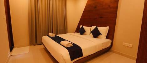 Une chambre d’hôtel moderne avec un grand lit, des rideaux beiges et un mur décoratif en bois.