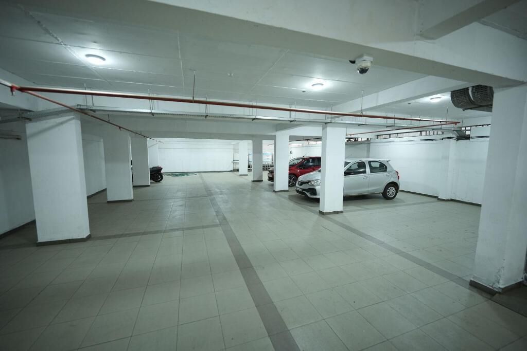 A parking garage with multiple levels, white pillars, and a red pipe running across the ceiling.