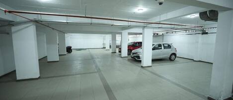 A parking garage with multiple levels, white pillars, and a red pipe running across the ceiling.