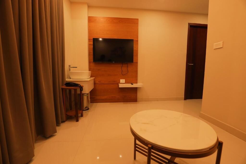 Una habitación compacta con un televisor de pared de madera, un lavamanos, una mesita y una puerta.