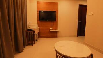 Una habitación compacta con un televisor de pared de madera, un lavamanos, una mesita y una puerta.