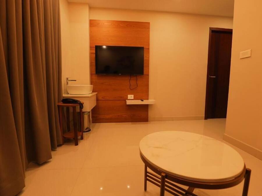 Una habitación compacta con un televisor de pared de madera, un lavamanos, una mesita y una puerta.