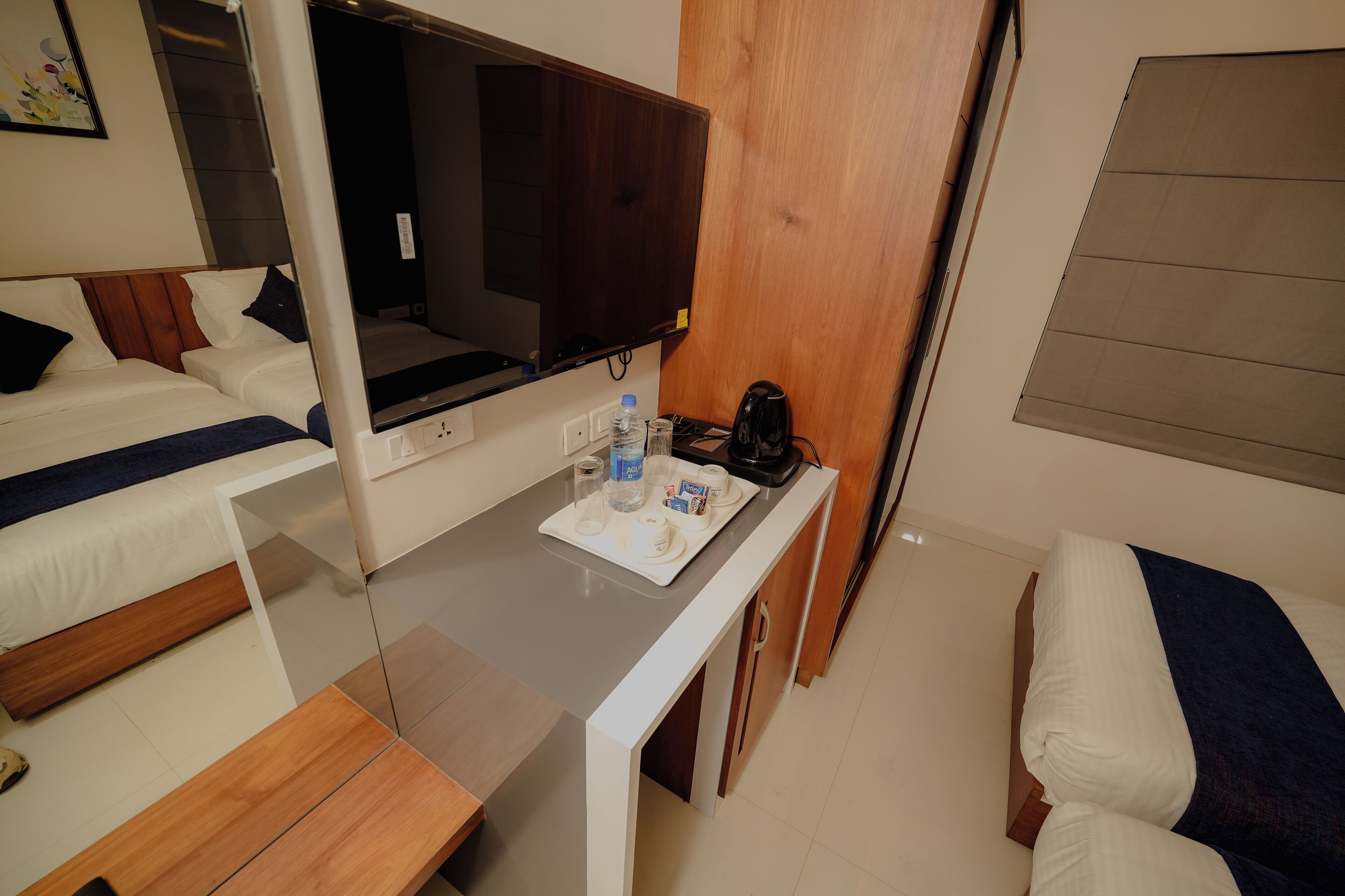 Ein Hotelzimmer mit Bett, Schreibtisch mit Frühstücksangebot, Fernseher und Fenster.