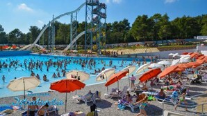 A swimming pool with a water slide and umbrellas.