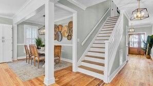 A staircase with wooden steps and white railings leading to a second floor. - Private Pool + Fire Pit + Foosball | Short Walk to Beach | Southern Oasis (Isle Of Palms)