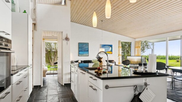 Una cocina moderna con una isla central, electrodomésticos de acero inoxidable y vistas al exterior.