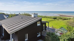 Una casa moderna con fachada oscura, techo inclinado y vista al mar.