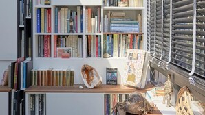 Eine moderne Bibliothek mit Bücherregalen, einem Holztisch und Dekorationselementen.