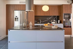 Una cocina moderna con una isla central, electrodomésticos de acero inoxidable y una salpicadera de mármol.
