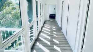Un pasillo largo y estrecho con grandes ventanales a un lado, que dejan entrar luz natural.