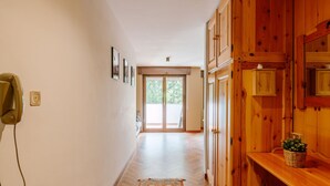 A hallway with wooden cabinets, a telephone, and a patterned rug. - Enrosadira by Interhome (Canazei)