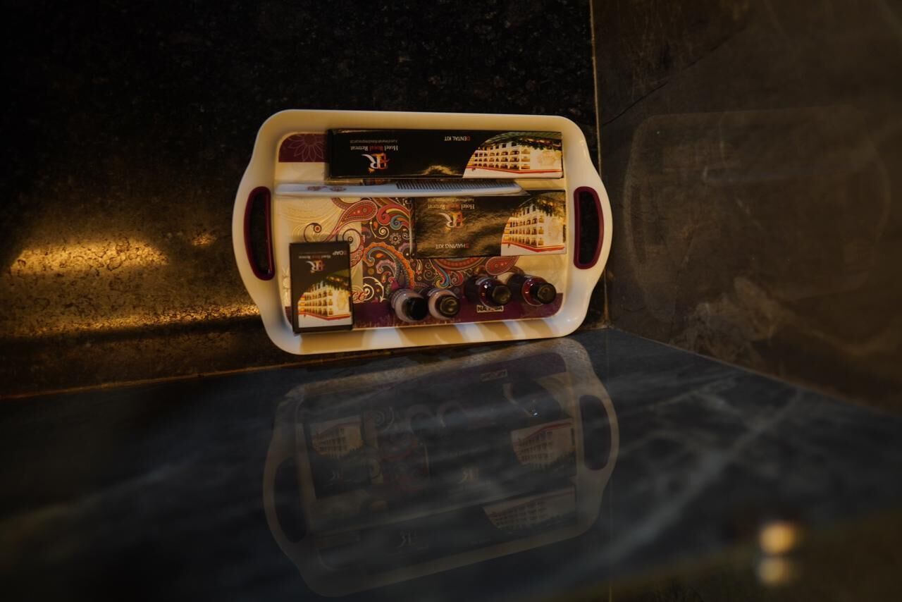 Uma bandeja com diversos itens, incluindo teclado, mouse e vários recipientes pequenos, possivelmente para produtos de higiene pessoal, sobre uma superfície refletora.