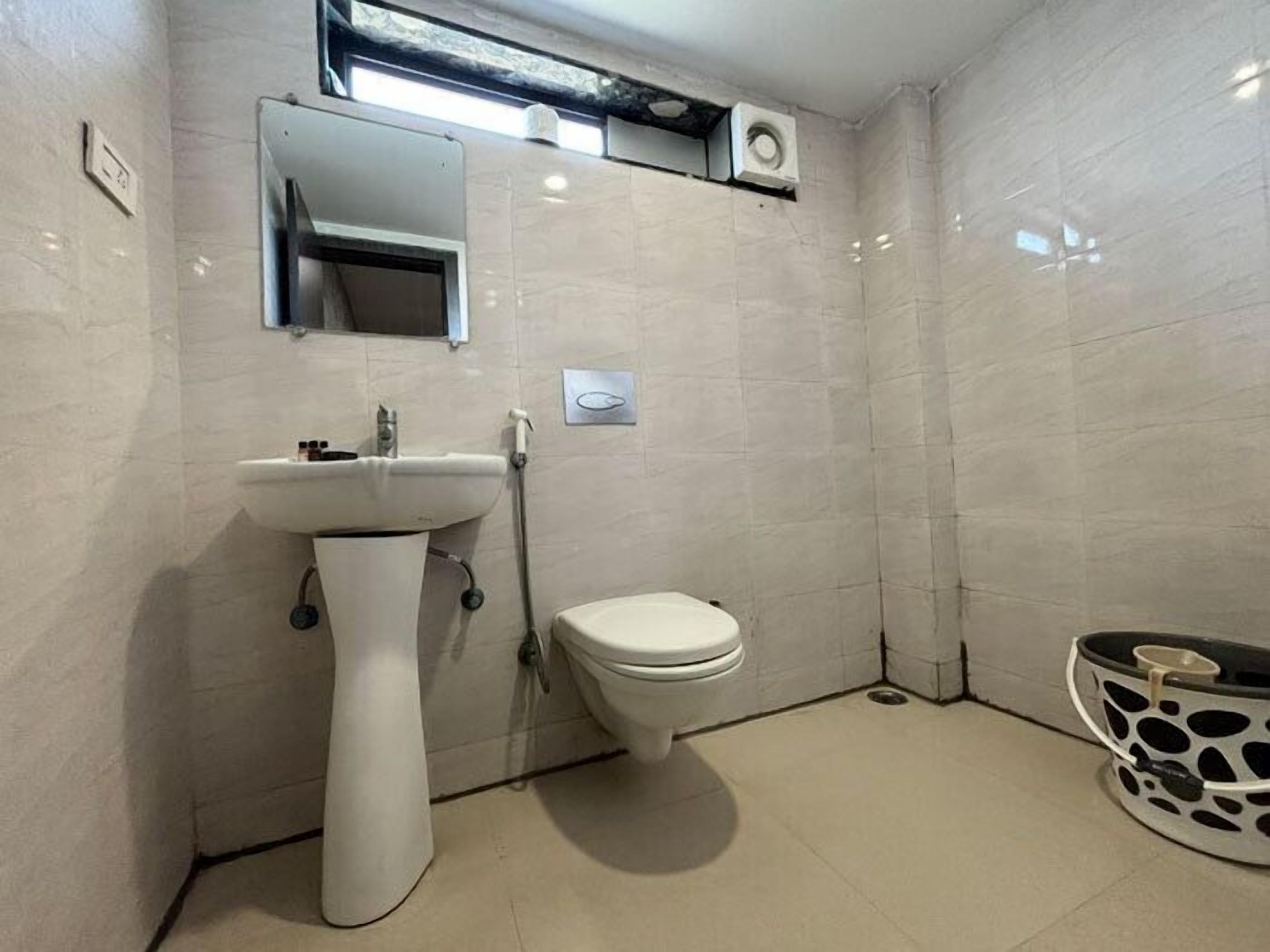 Un bany amb un lavabo de pedestal, un vàter i un mirall sobre el lavabo.