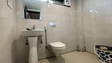 Un bany amb un lavabo de pedestal, un vàter i un mirall sobre el lavabo.
