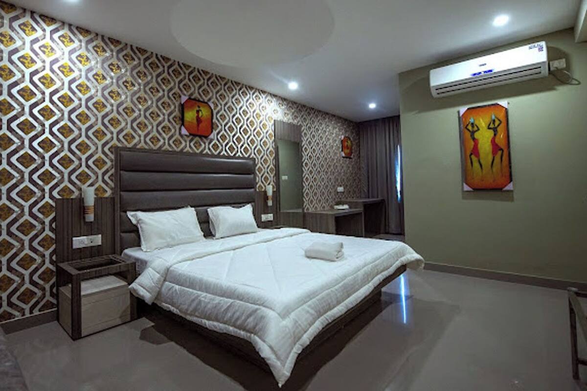 Un dormitorio moderno con una cama grande, una mesita de noche, aire acondicionado instalado en la pared y un papel pintado estampado.