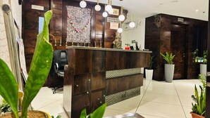 A reception area with a wooden desk, a black office chair, and a hanging light fixture.