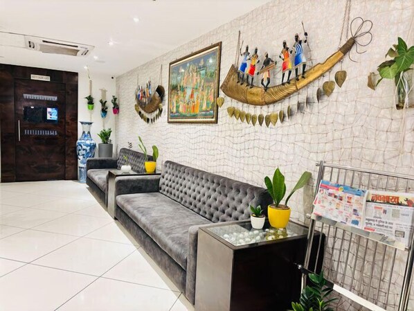 Un área de recepción con un sofá gris, un mostrador de madera, un cuadro colgado en la pared y un adorno mural.