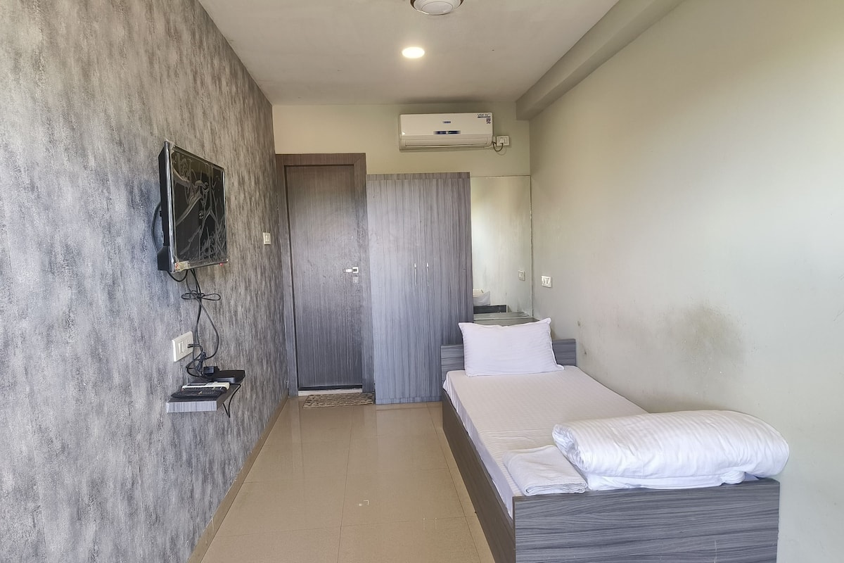Un dormitorio con cama, televisor montado en la pared, armario y aire acondicionado.