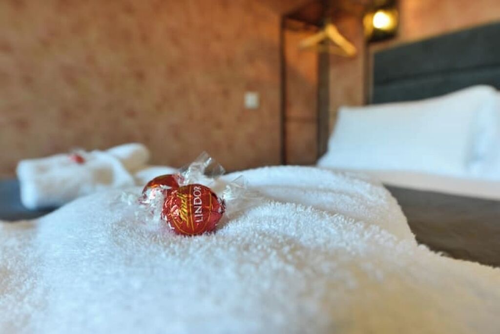 Een bed met een witte deken en een Lindor chocolade.